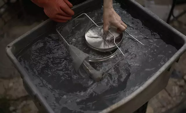 An ultra-Orthodox Jewish man dips cooking utensils in fresh water after putting them in boiling water to remove remains of leaven in preparation for the upcoming Jewish holiday of Passover, in the ultra-Orthodox neighbourhood Mea Shearim, in Jerusalem, Thursday, April 10, 2025. (AP Photo/Leo Correa)