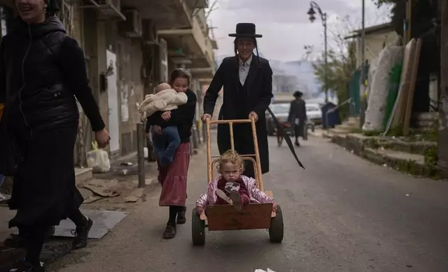 Ultra-Orthodox Jewish people Walk in the Orthodox neighbourhood of Mea Shearim in Jerusalem in final preparation for the Passover holiday, Friday, April 11, 2025. (AP Photo/Ohad Zwigenberg)