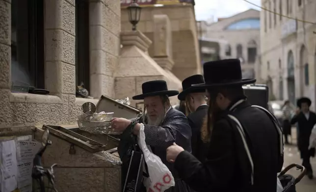 Ultra-Orthodox Jewish men clean their new cooking utensils in a water tank, as preparation for the upcoming Jewish holiday of Passover, in the ultra-Orthodox neighbourhood Mea Shearim, in Jerusalem, Thursday, April 10, 2025. (AP Photo/Leo Correa)