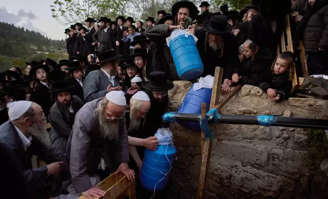 Ultra-Orthodox Jewish men gather to collect water from a spring to make matzoh, a traditional handmade unleavened bread for the holiday of Passover, during the Maim Shelanu ceremony at a mountain spring in the outskirts of Jerusalem, Thursday, April 10, 2025. (AP Photo/Ohad Zwigenberg)