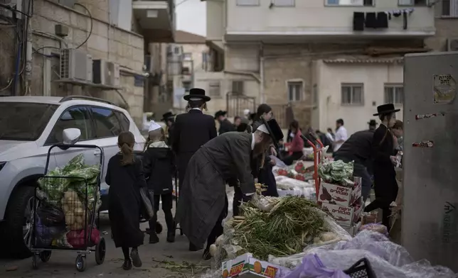 Ultra-Orthodox Jewish people collect fruits and vegetables donated to the community ahead of the Jewish holiday of Passover, in the ultra-Orthodox neighbourhood Mea Shearim, in Jerusalem, Thursday, April 10, 2025. (AP Photo/Leo Correa)