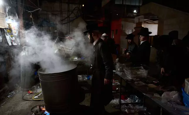 Ultra-Orthodox Jewish men clean their new cooking utensils in a water tank, as preparation for the upcoming Jewish holiday of Passover, in the ultra-Orthodox neighborhood Mea Shearim, in Jerusalem, Thursday, April 10, 2025. (AP Photo/Ohad Zwigenberg)