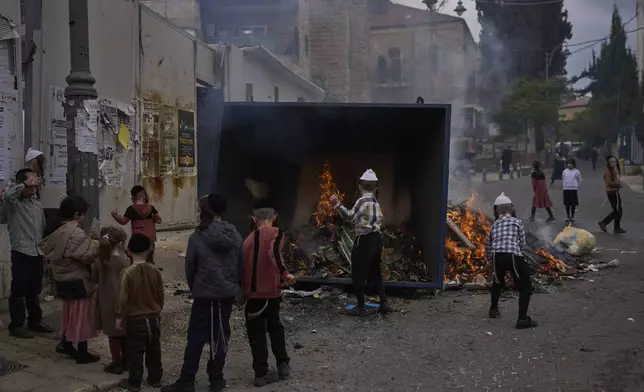 Ultra-Orthodox Jewish men and children burn leavened items in final preparation for the Passover holiday in the Orthodox neighbourhood of Mea Shearim in Jerusalem, Friday, April 11, 2025. (AP Photo/Ohad Zwigenberg)