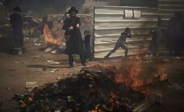 Ultra-Orthodox Jewish men and children burn leavened items in final preparation for the Passover holiday in the ultra-Orthodox Jewish town of Bnei Brak, near Tel Aviv, Israel, Friday, April 11, 2025. (AP Photo/Leo Correa)