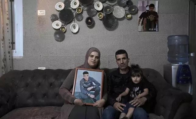 FILE - Maysoon, left, and Saleh Manasra, parents of Ahmad Manasra, who has been imprisoned by Israel since he was 13 when he was was convicted of attempted murder and sentenced to nine and a half years in prison, after his older cousin stabbed two Israelis, pose for a portrait with their daughter, Sham, in their home in east Jerusalem, Tuesday, Nov. 8, 2022. (AP Photo/ Maya Alleruzzo, File)