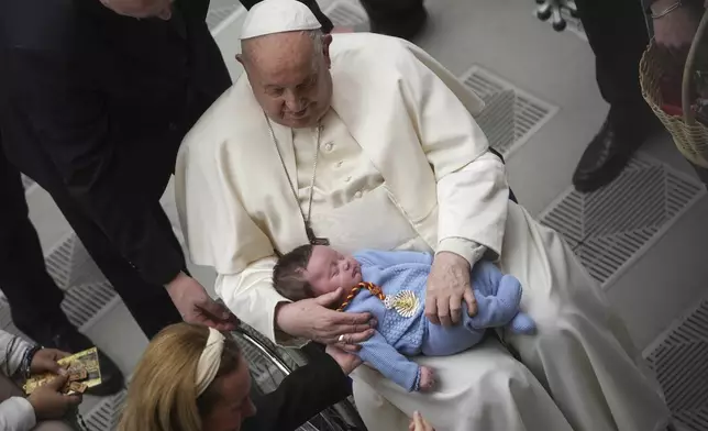 FILE - Pope Francis holds a baby as he leaves at the end of his weekly general audience in the Paul VI Hall, at the Vatican, Wednesday, Jan. 29, 2025. (AP Photo/Alessandra Tarantino, file)