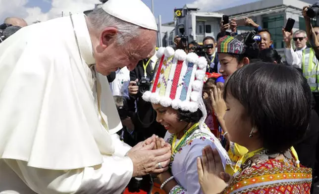 FILE - Pope Francis is greeted by young children in traditional clothes upon his arrival at Yangon's airport, Myanmar, Monday, Nov. 27, 2017. (AP Photo/Andrew Medichini, file)