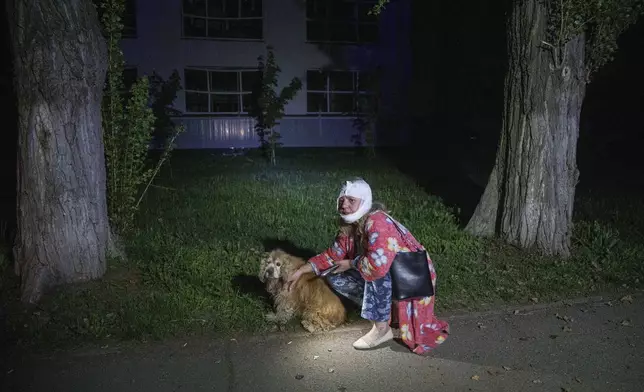 An injured woman sits with her dog near a house destroyed by a Russian airstrike in a residential neighborhood in Kyiv, Ukraine, on Thursday, April 24, 2025. (AP Photo/Evgeniy Maloletka)