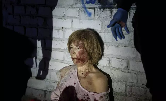 An injured woman sits near her house, which was damaged by a Russian airstrike, in a residential neighbourhood in Kyiv, Ukraine, on Thursday, April 24, 2025. (AP Photo/Evgeniy Maloletka)