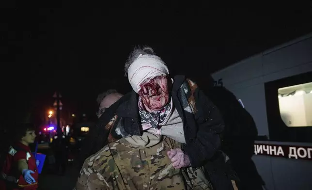 A Ukrainian serviceman carries an injured woman from her house, which was damaged by a Russian airstrike, in residential neighbourhood in Kyiv, Ukraine, early Thursday, April 24, 2025. (AP Photo/Evgeniy Maloletka)