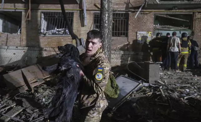A Ukrainian serviceman carries a dog out of a house damaged by a Russian airstrike in a residential neighborhood in Kyiv, Ukraine, on Thursday, April 24, 2025. (AP Photo/Evgeniy Maloletka)