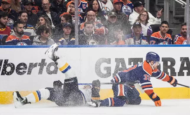 St. Louis Blues' Jake Neighbours (63) and Edmonton Oilers' Viktor Arvidsson (33) collide during the third period of an NHL game in Edmonton on Wednesday, April 9, 2025. (Jason Franson/The Canadian Press via AP)