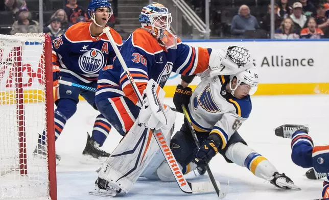 St. Louis Blues' Jake Neighbours (63) gets shoved by Edmonton Oilers goalie Calvin Pickard (30) during the third period of an NHL game in Edmonton on Wednesday, April 9, 2025. (Jason Franson/The Canadian Press via AP)