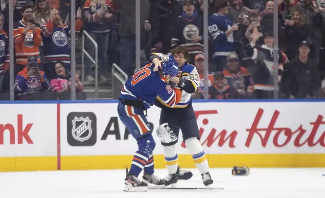 St. Louis Blues' Jake Neighbours (63) and Edmonton Oilers' Corey Perry (90) fight during first period NHL action in Edmonton on Wednesday, April 9, 2025. (Jason Franson/The Canadian Press via AP)