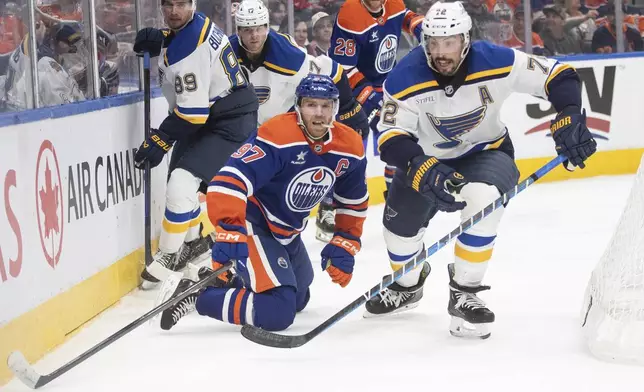 St. Louis Blues' Justin Faulk (72) and Edmonton Oilers' Connor McDavid (97) battle for the puck during the second period of an NHL game in Edmonton on Wednesday, April 9, 2025. (Jason Franson/The Canadian Press via AP)