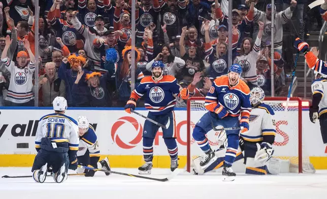 St. Louis Blues goalie Jordan Binnington (50) looks on as Edmonton Oilers' Connor Brown (28) and Adam Henrique (19) celebrate a goal during the third period of an NHL game in Edmonton on Wednesday, April 9, 2025. (Jason Franson/The Canadian Press via AP)