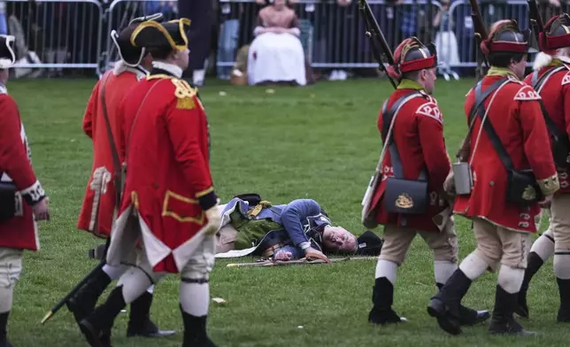 British Regulars march past a fallen New England colonial militia, also known as a Minuteman, during a reenactment celebration of the 250th anniversary of the Battle of Lexington and start of the American Revolution, Saturday, April 19, 2025, in Lexington, Mass. (AP Photo/Charles Krupa)
