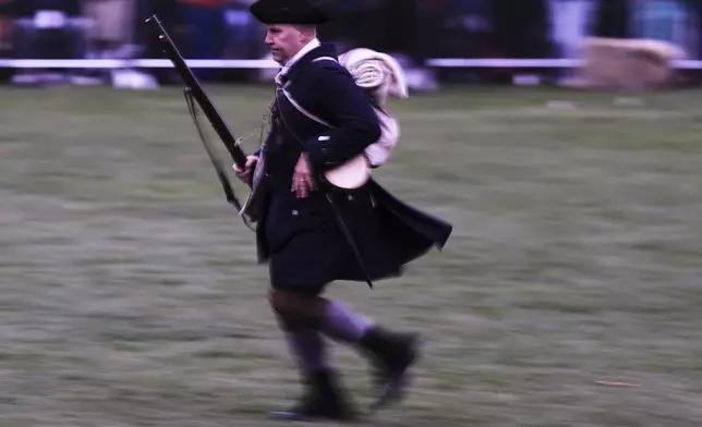 New England colonial militia man, also known as a Minuteman, runs towards fellow troops before sunrise during a reenactment celebration of the 250th anniversary of the Battle of Lexington and start of the American Revolution, Saturday, April 19, 2025, in Lexington, Mass. (AP Photo/Charles Krupa)