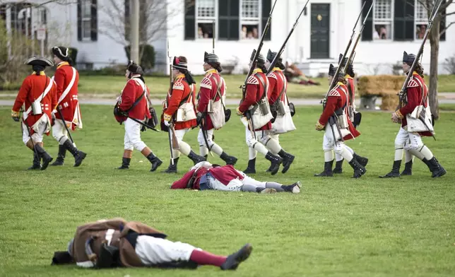 FILE - British re-enactors march past dead Colonial soldiers during the Patriots' Day re-enactment during the Patriots' Day reenactment of the battles of Lexington and Concord, on the Lexington Green in Lexington, Mass. Monday, Aril 17, 2017. (Keith Viglione/The Boston Herald via AP,FIle)