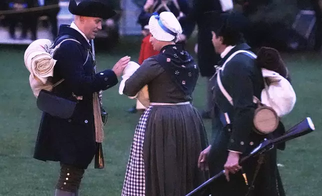 A New England colonial militia man, also known as a Minuteman, caresses the head of a baby prior to facing the British Regulars during a reenactment celebration of the 250th anniversary of the Battle of Lexington and start of the American Revolution, Saturday, April 19, 2025, in Lexington, Mass. (AP Photo/Charles Krupa)