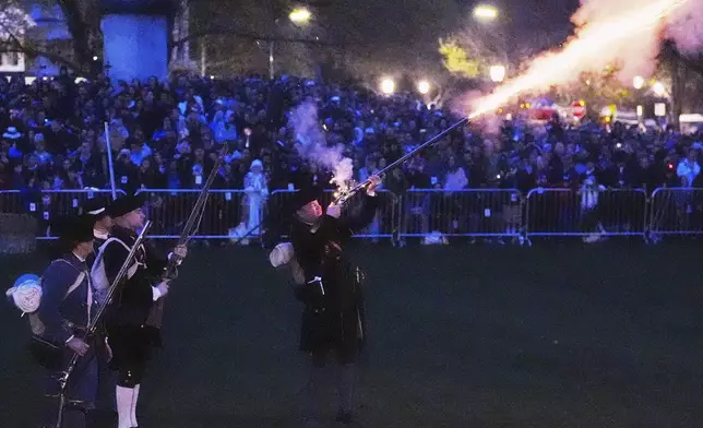 New England colonial militia, also known as a Minuteman, fires a rifle before sunrise during a reenactment celebration of the 250th anniversary of the Battle of Lexington and start of the American Revolution, Saturday, April 19, 2025, in Lexington, Mass. (AP Photo/Charles Krupa)