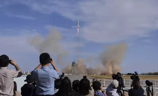 Journalists film China's Long March 2F rocket, carrying three astronauts for the Shenzhou 20 manned space mission, lifts off for a space station, at the Jiuquan Satellite Launch Center in Jiuquan, northwestern China, Thursday, April 24, 2025. (AP Photo/Andy Wong)