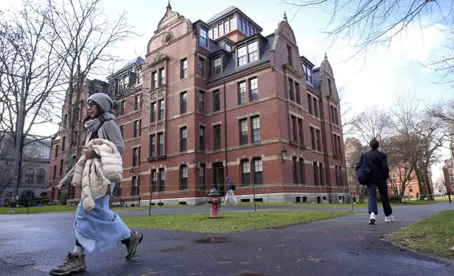 FILE - People walk between buildings, Dec. 17, 2024, on the campus of Harvard University in Cambridge, Mass. (AP Photo/Steven Senne, File)