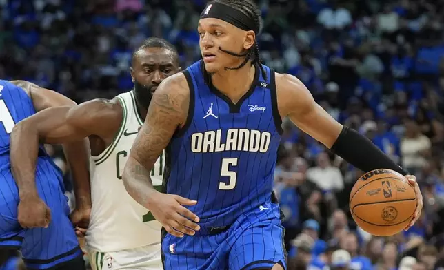 Orlando Magic forward Paolo Banchero (5) drives past Boston Celtics guard Jaylen Brown, left, during the second half in Game 4 of a first-round NBA basketball playoff series, Sunday, April 27, 2025, in Orlando, Fla. (AP Photo/John Raoux)