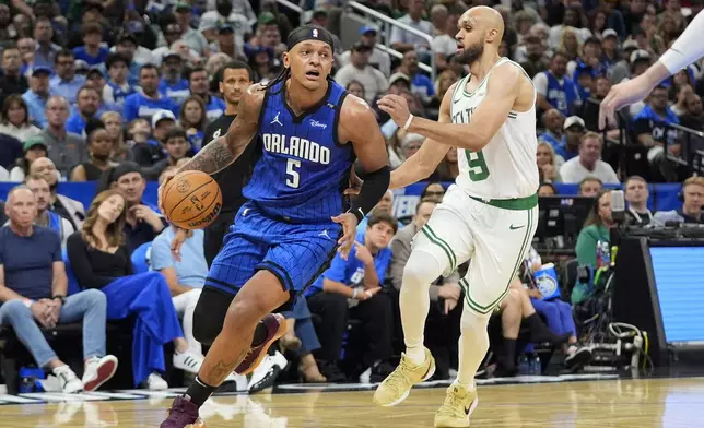 Orlando Magic forward Paolo Banchero (5) drives around Boston Celtics guard Derrick White (9) during the second half in Game 4 of a first-round NBA basketball playoff series, Sunday, April 27, 2025, in Orlando, Fla. (AP Photo/John Raoux)