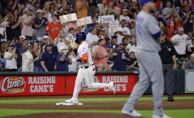 Houston Astros' Isaac Paredes, center, waves his hand in front of his face as he rounds the bases on his solo home run as Toronto Blue Jays pitcher Yariel Rodríguez, right, walks off the mound during the seventh inning of a baseball game Tuesday, April 22, 2025, in Houston. (AP Photo/Michael Wyke)