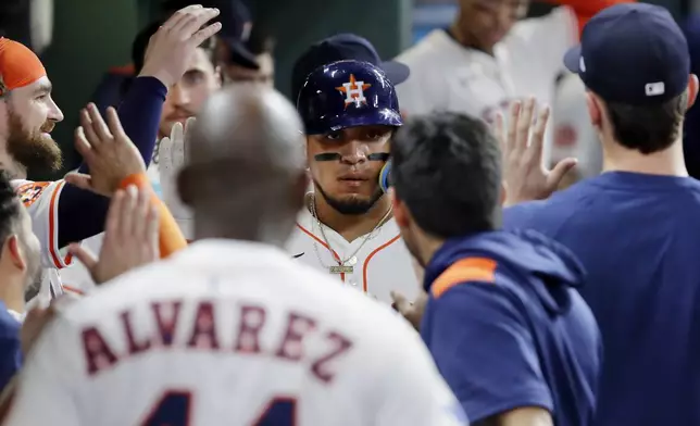 Houston Astros' Isaac Paredes, center, collects high fives in the dugout after his solo home run against the Toronto Blue Jays during the seventh inning of a baseball game Tuesday, April 22, 2025, in Houston. (AP Photo/Michael Wyke)