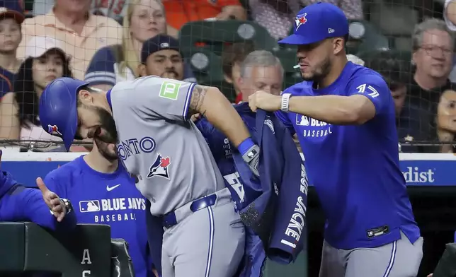 Toronto Blue Jays's Nathan Lukes, left, gets help putting on The Blue Jacket from Jose Berrios, right, after Lukes' solo home run against the Houston Astros during the third inning of a baseball game Tuesday, April 22, 2025, in Houston. (AP Photo/Michael Wyke)