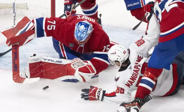 Montreal Canadiens goaltender Jakub Dobes (75) stops a shot as Washington Capitals' Andrew Mangiapane (88) comes in for a rebound during the second period of Game 4 in an NHL hockey first-round playoff series in Montreal, Sunday, April 27, 2025. (Christinne Muschi/The Canadian Press via AP)
