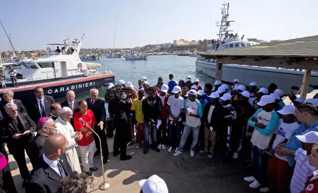 FILE - Pope Francis, left, speaks to migrants, wearing white caps, during his visit to the island of Lampedusa, southern Italy, Monday July 8, 2013. (AP Photo/Alessandra Tarantino, Pool, File)