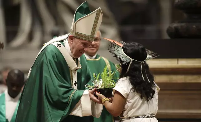 FILE - An Amazzonian indigenous girl gives Pope Francis a plant during the offertory of a Mass for the closing of Amazon synod in St. Peter's Basilica at the Vatican, Sunday, Oct. 27, 2019. (AP Photo/Alessandra Tarantino, file)