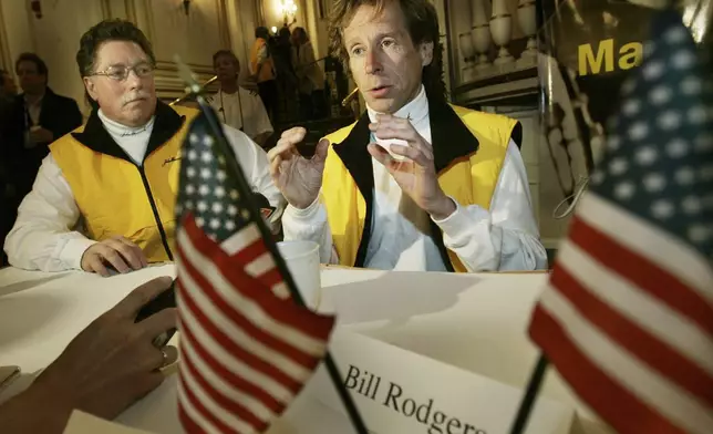 FILE - Four-time Boston Marathon winner, Bill Rodgers, speaks, as Boston Marathon wheelchair winner and pioneer, Bob Hall, listens at left, during a news conference in Boston, April 15, 2005. (AP Photo/Elise Amendola, File)