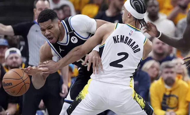 Milwaukee Bucks' Giannis Antetokounmpo, left, dribbles as Indiana Pacers' Andrew Nembhard (2) defends during the first half of a first-round NBA basketball playoff game, Saturday, April 19, 2025, in Indianapolis. (AP Photo/Michael Conroy)