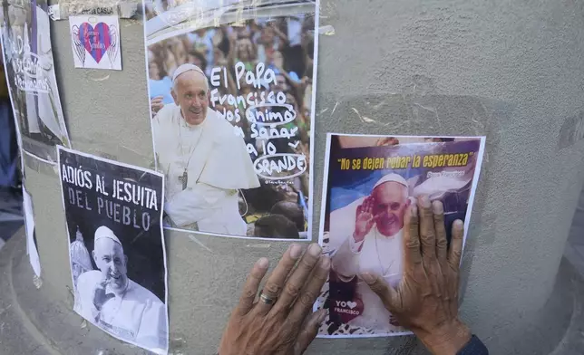 Norberto Rodriguez places a photo of the late Pope Francis on a column at the Cathedral in Buenos Aires, Argentina, Tuesday, April 22, 2025. (AP Photo/Natacha Pisarenko)