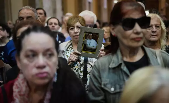 A woman holds a photo of the late Pope Francis during an inter-religious Mass in honor of the late pontiff at the Cathedral in Buenos Aires, Argentina, Tuesday, April 22, 2025. (AP Photo/Rodrigo Abd)