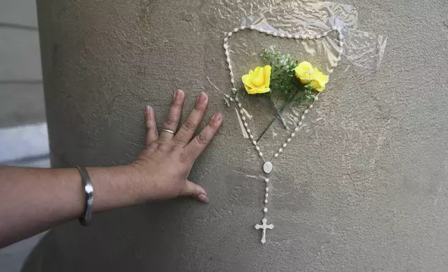 Patricia Sanchez attaches a rosary to a column of the Cathedral following the Vatican's announcement of Pope Francis' death in Buenos Aires, Argentina, Monday, April 21, 2025. (AP Photo/Natacha Pisarenko)