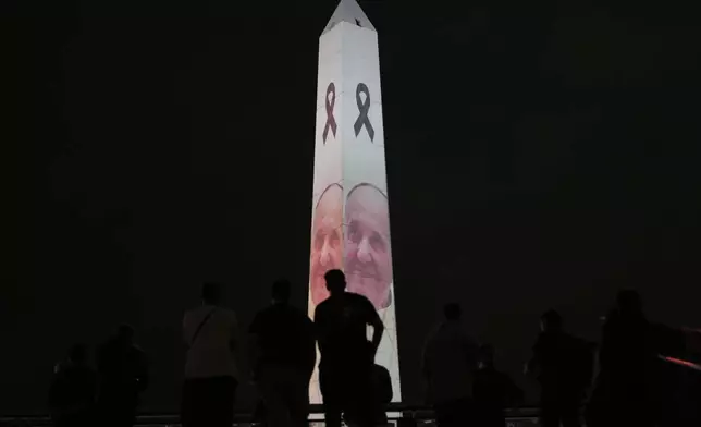 A man looks at a photo of the late Pope Francis projected onto the Obelisk in Buenos Aires, Argentina, Monday, April 21, 2025. (AP Photo/Gustavo Garello)