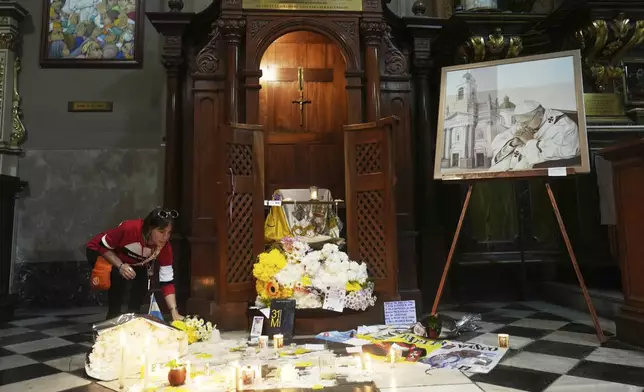 A woman places flowers by the confessional of the Basilica de San Jose de Flores where Francis first realized his calling to become a priest at age 17 in Buenos Aires, Argentina, Tuesday, April 22, 2025. (AP Photo/Natacha Pisarenko)