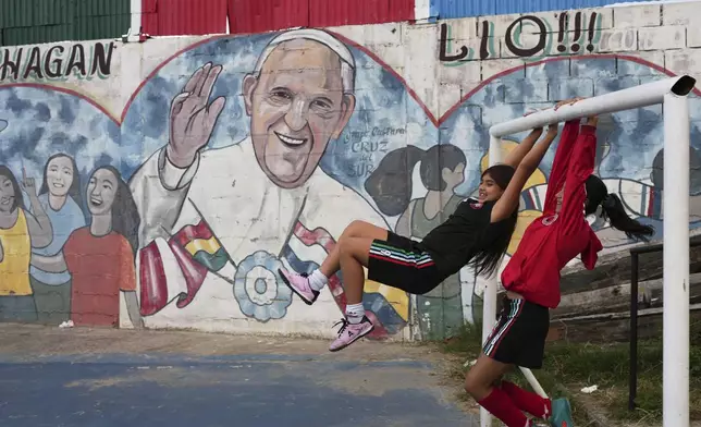 Girls play next to a mural of the late Pope Francis in Buenos Aires, Argentina, Monday, April 21, 2025. (AP Photo/Rodrigo Abd)