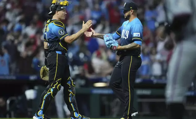 Philadelphia Phillies' J.T. Realmuto, left, and José Ruiz, right, celebrate after they won a baseball game against the Miami Marlins, Friday, April 18, 2025, in Philadelphia. (AP Photo/Matt Rourke)