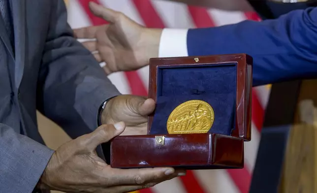 House Speaker Mike Johnson, R-La., right, presents the Congressional Gold Medal to Stanley Earley III, son of Lt. Col. Charity Adams Earley, left, during a ceremony honoring the Six Triple Eight, on Capitol Hill, Tuesday, April 29, 2025, in Washington. The U.S. Army's 6888th Central Postal Directory Battalion, also known as the Six Triple Eight, was a group of Black servicewomen, serving overseas, to sort millions of pieces of mail and deliver them to the troops in the field of battle during World War II. (AP Photo/Rod Lamkey, Jr.)