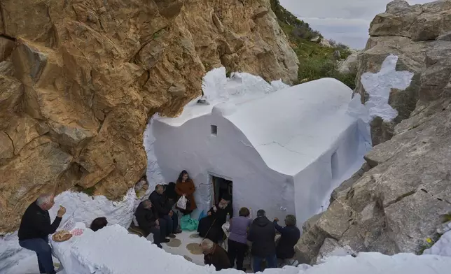 Orthodox Christian monk Father Spyridon of Amorgos, center, talks with islanders after the Divine Liturgy in the chapel of Panagia Evangelistria, in Amorgos island, Greece, on Tuesday, March 25, 2025. (AP Photo/Petros Giannakouris)