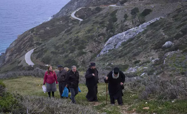 Orthodox Christian monk Father Spyridon of Amorgos, right, Father Antonis and other faithful leave the chapel of Panagia Evangelistria, after participating in Divine Liturgy in Amorgos island, Greece, on Monday, March 24, 2025. (AP Photo/Petros Giannakouris)