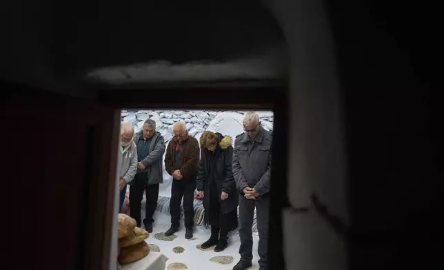 The faithful stand outside the chapel of Panagia Evangelistria, in Amorgos island, Greece, as Orthodox Christian monk Father Spyridon of Amorgos conducts the Divine Liturgy, on Tuesday, March 25, 2025. (AP Photo/Petros Giannakouris)