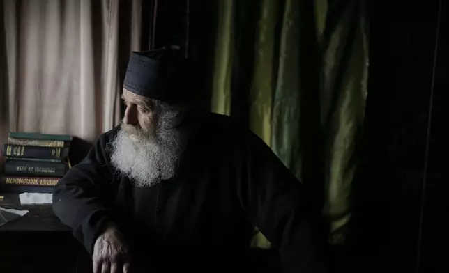 Orthodox Christian monk Father Spyridon of Amorgos, looks out from the chapel of the Monastery of Panagia Hozoviotissa, in Amorgos island, Greece, Sunday, March 30, 2025. (AP Photo/Petros Giannakouris)