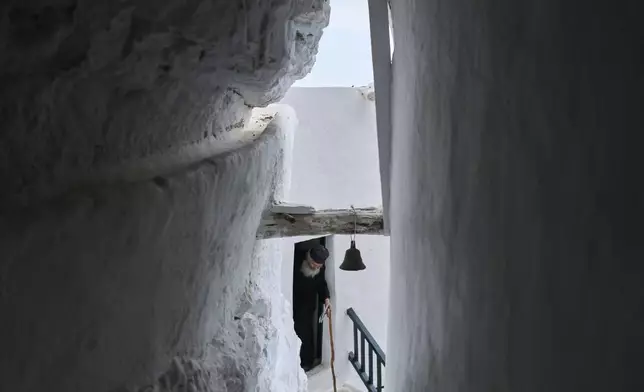 Orthodox Christian monk Father Spyridon of Amorgos, exits the chapel at the Monastery of Panagia Hozoviotissa, in Amorgos island, Greece, Thursday, March 27, 2025. (AP Photo/Petros Giannakouris)
